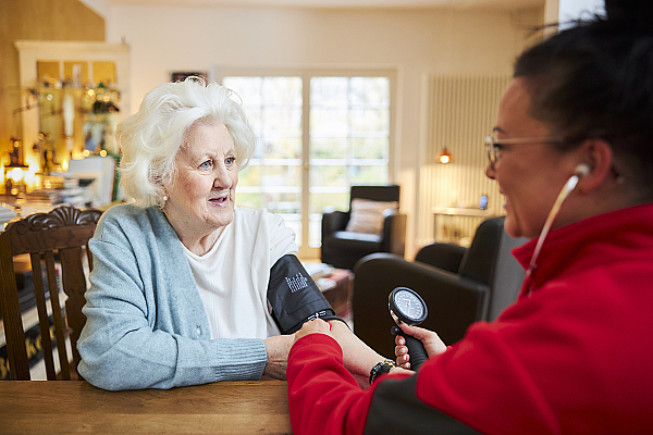 Eine Pflegefachkraft der Johanniter misst bei einer Seniorin den Blutdruck.