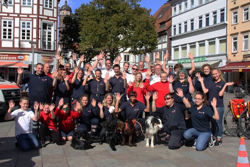 Gruppenfoto mit allen Helferinnen und Helfern sowie einigen Rettunghunden. 