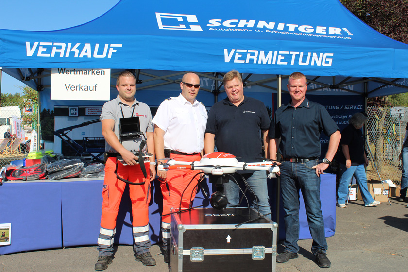 Johanniter erhalten die Drohne von Daniel Wenzel und Walter Päuser, Chef der Päuser-Gruppe. (Die Männer stehen hinter der Drohne und lächeln in die Kamera.)