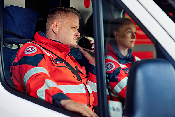 Ein Mitarbeiter aus dem Rettungsdienst nimmt im Rettungswagen Kontakt über ein Funkgerät auf.