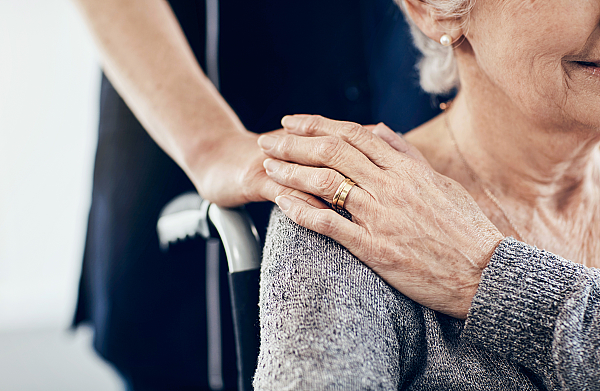 Eine Pflegerin spendet einer Seniorin im Rollstuhl Trost.