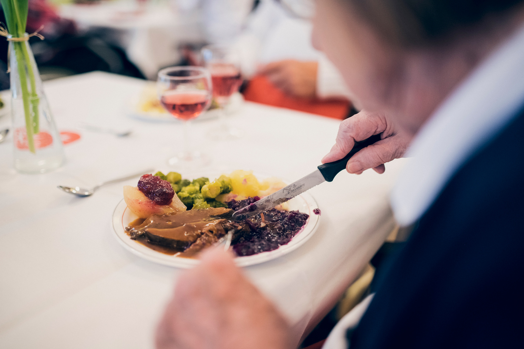 Wir kochen frisch und vitaminreich, schmackhaft und abwechslungsreich Gedeckter Tisch mit Essen und Weinglas