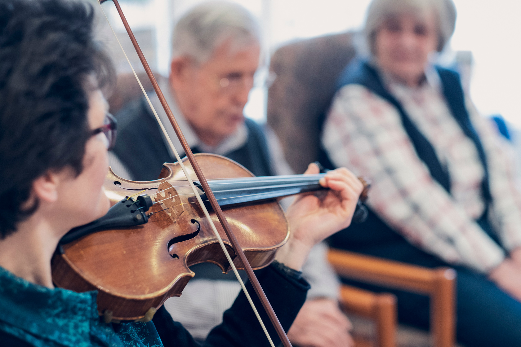 Regelmäßige Hauskonzerte in den Johanniter-Häusern Zwei Bewohnende lauschen einer Violinistin beim Konzert