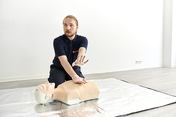 FSJler erklärt die Herz Lungen Wiederbelebung an einer Übungspuppe