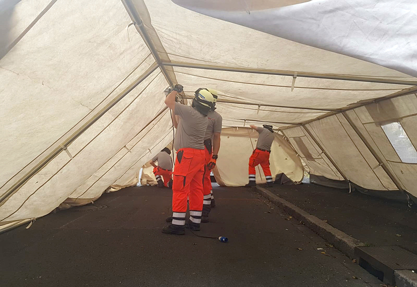 Johanniter stellen ein großes weißes Zelt auf.