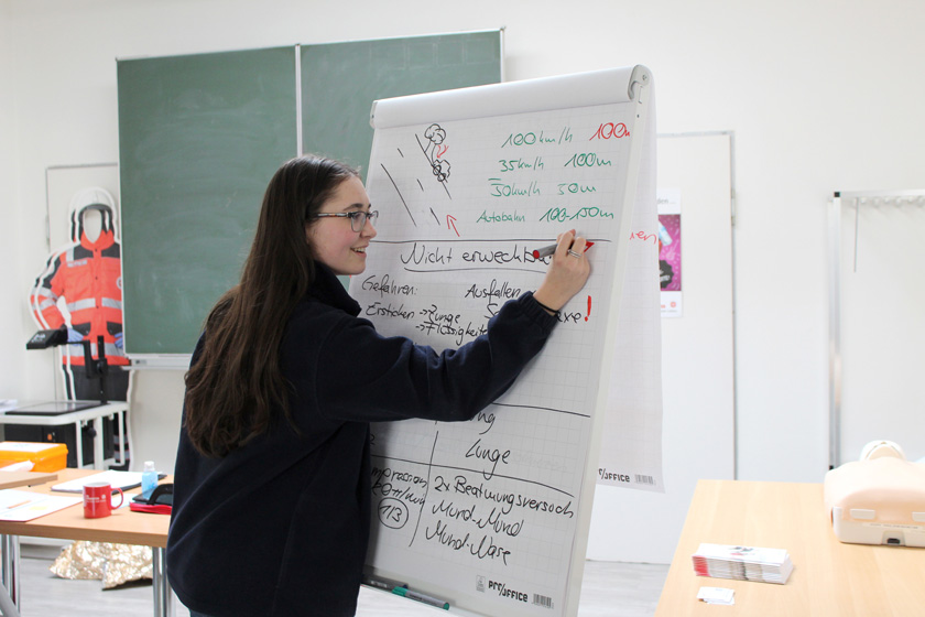 BFDlerin Jenny schreibt Infos an ein Flipchart, wie man sich verhalten sollte, wenn eine Person nicht "erweckbar ist". 