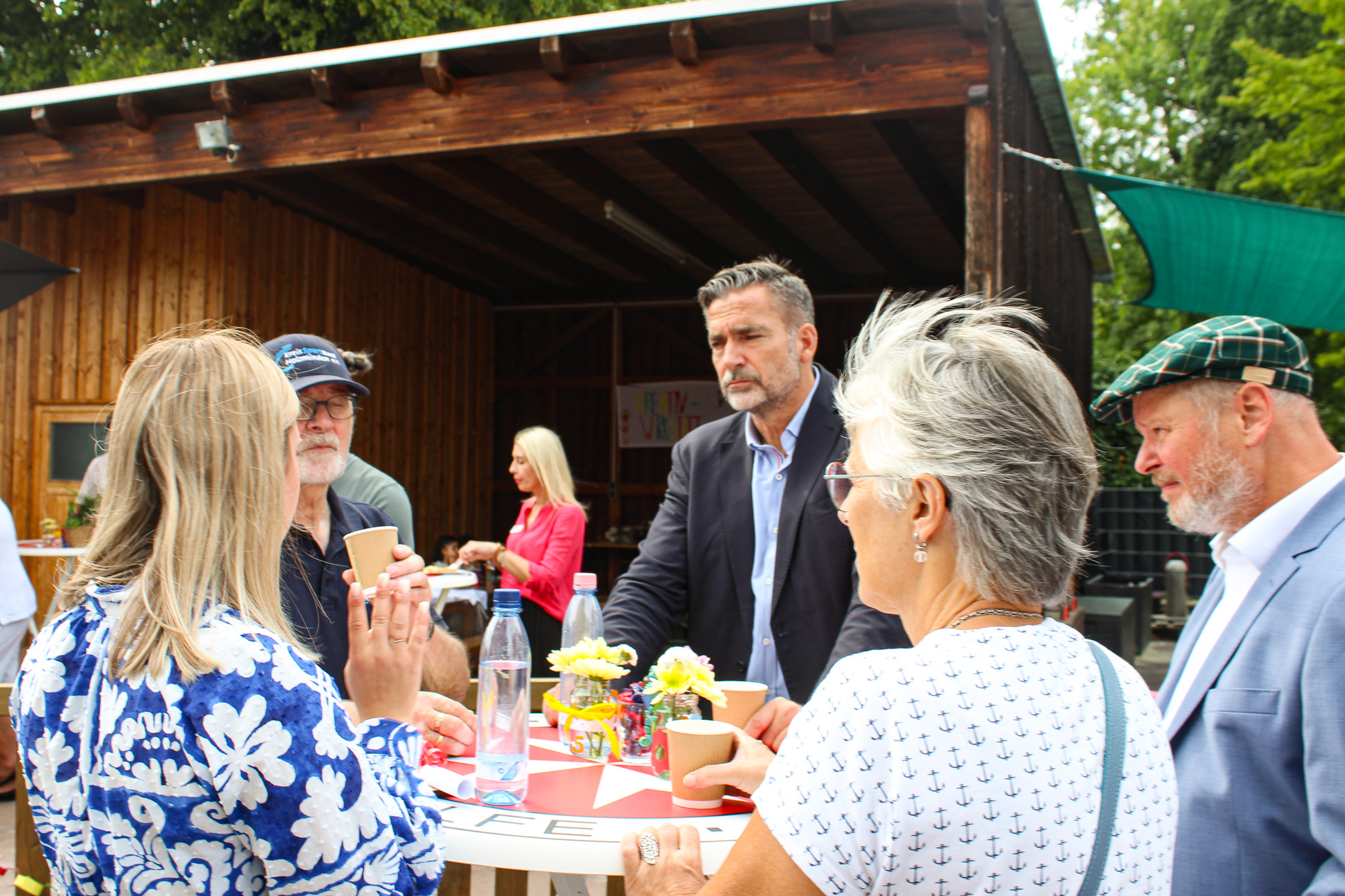 Zwei Frauen und drei Männer an einem Stehtisch unterhalten sich