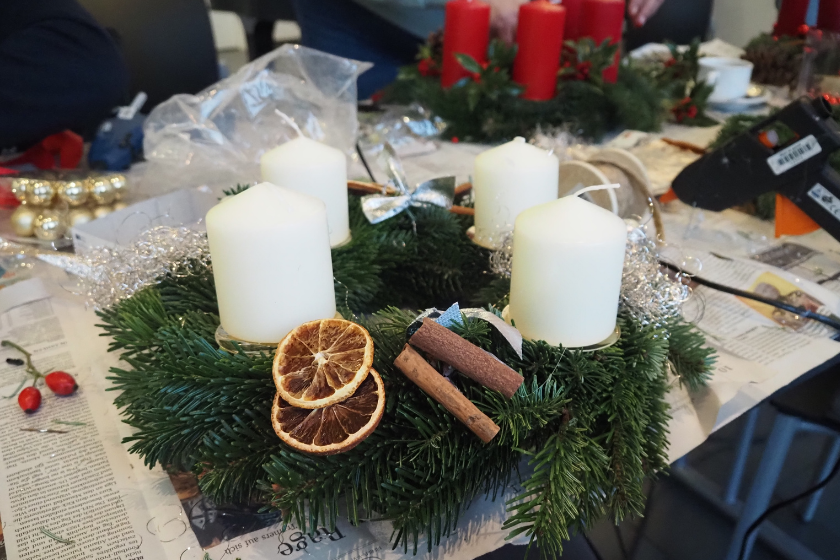 Dieser Kranz ist in Naturtönen gehalten, mit Orangenschalen und Zimtstangen. Die Kerzen sind weiß.