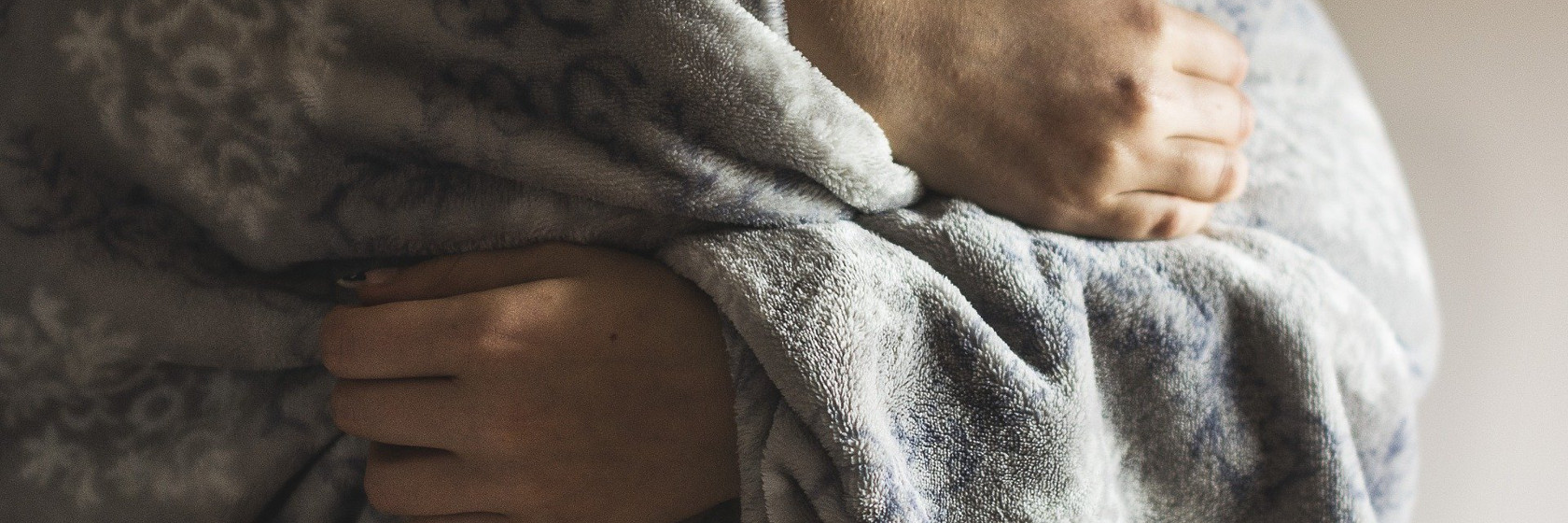 Eine Person hüllt sich in eine warme Decke.