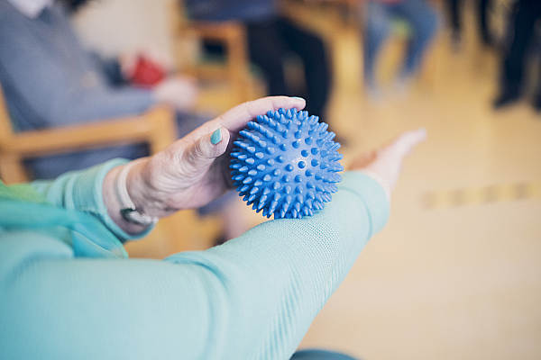 Eine Seniorin beschäftigt sich mit einem blauen Igelball