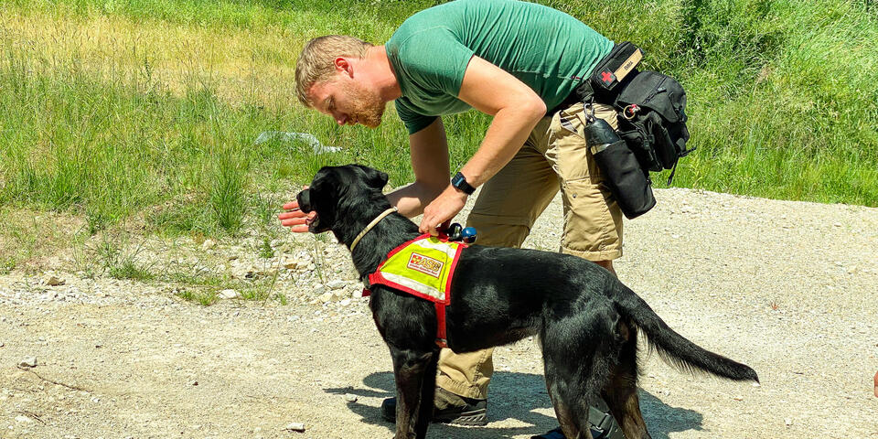 Ein Hundeführer zeigt seinem Hund die Richtung