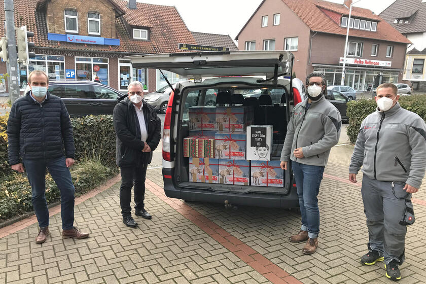 4 Männer vor einem Auto, das beladen ist mit Paketen