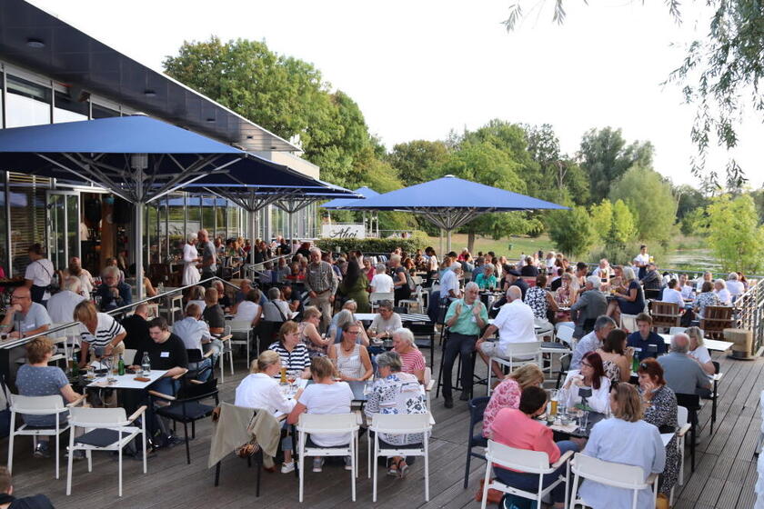 Viele Menschen sitzen auf einer Terrasse 