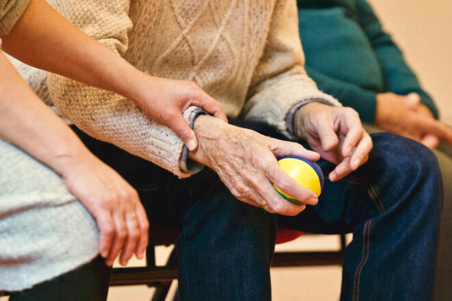 Eine ältere Person hält einen Jonglierball in der Hand.