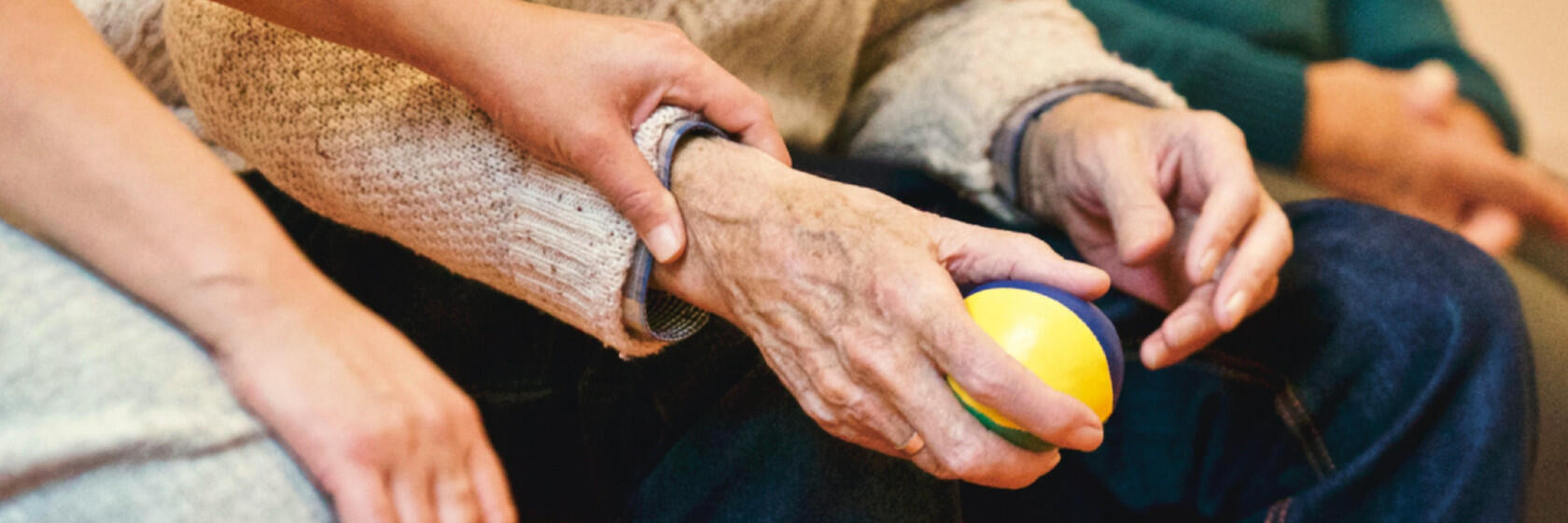 Eine ältere Person hält einen Jonglierball in der Hand.