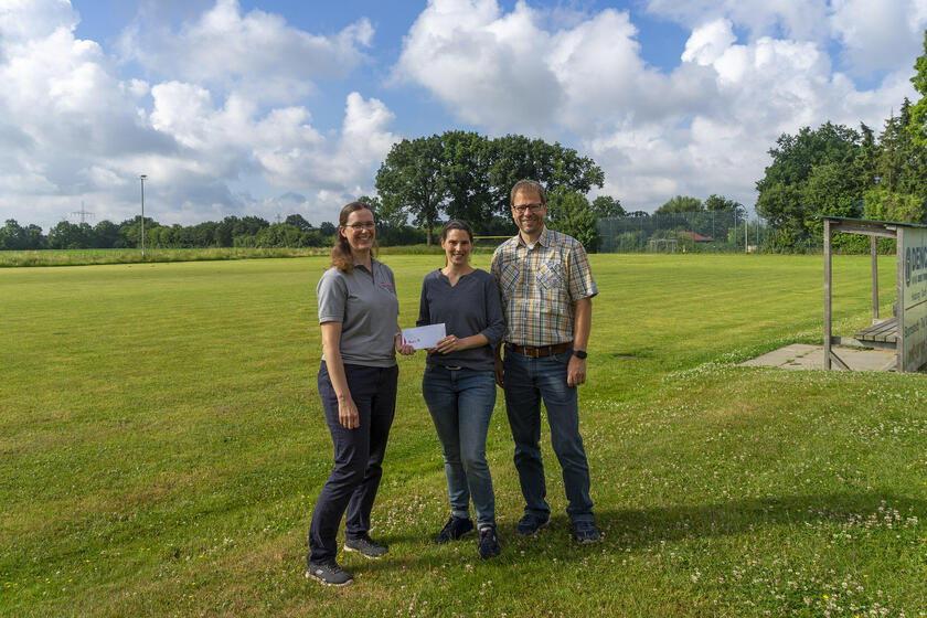 Eva Wegner (Mitte) und Bernd Lienau (r.) vom Vosslocher Sportverein überreichten auf dem Sportplatz symbolisch die großzügige Spende in Höhe von 3.600 Euro an Annika Siemßen, Leiterin der Johanniter-Kita Fuchsbau (l.).