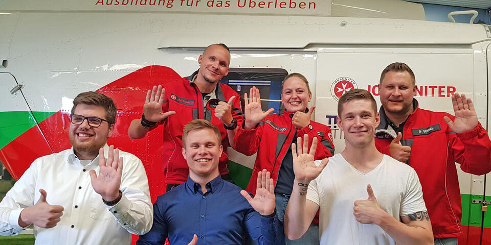 Fünf Männer und eine Frau lachen in die Kamera und haben den Daumen nach oben