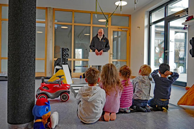 Ein Mann in einer Kita erklärt Kindern etwas
