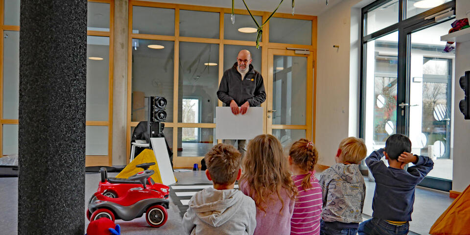 Ein Mann in einer Kita erklärt Kindern etwas
