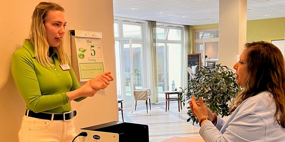 Zwei Frauen stehen sich gegenüber; zwischen ihnen auf einem kleinen Tisch eine Box, die von innen schwarz ist.