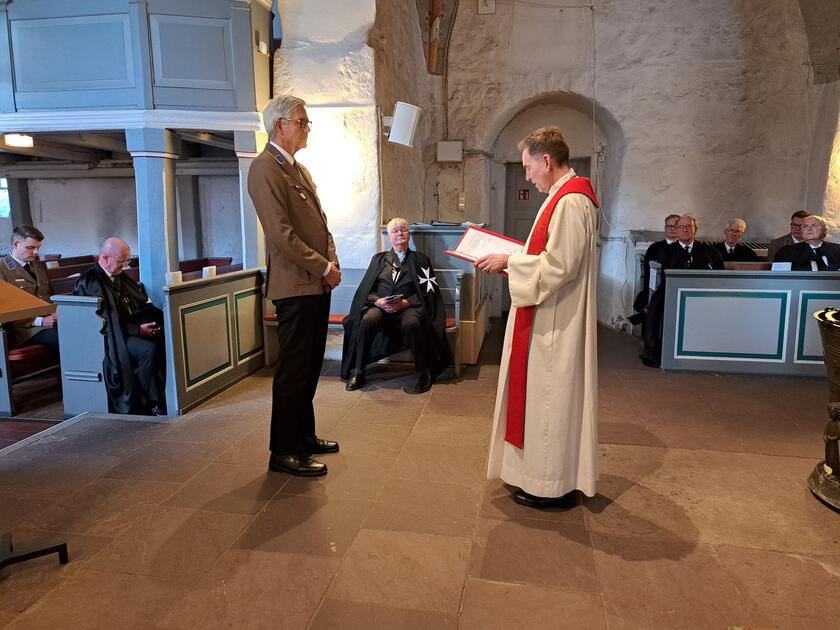 Stefan von Stegmann steht in Johanniter-Dienstkleidung vor Pastor Ralf-Torsten Brinkmann im Altarraum der Kirche.