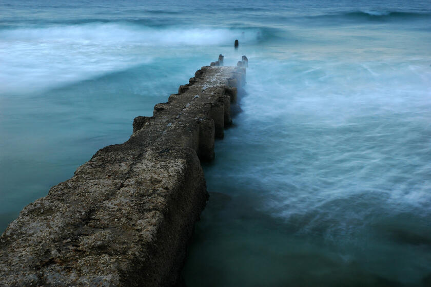eine Steinmauer dient im Meer als Wellenbrecher