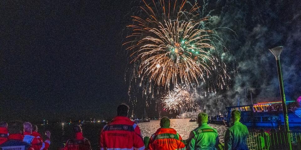 Die Einsatzkräfte schauen sich entspannt das Feuerwerk an.
