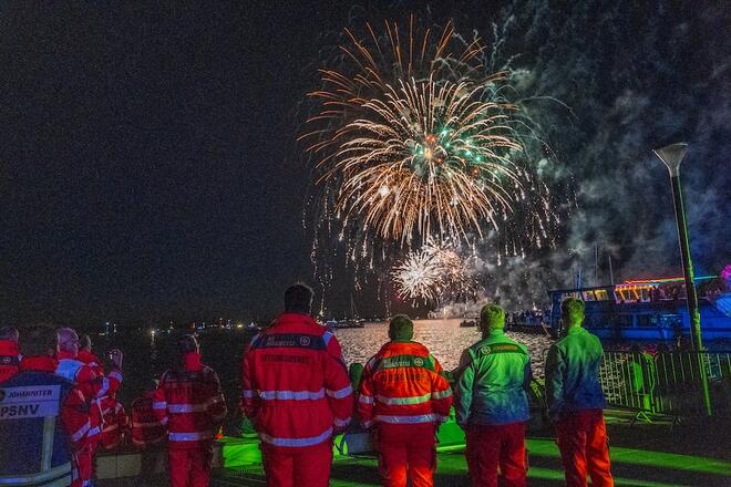 Die Einsatzkräfte schauen sich entspannt das Feuerwerk an.