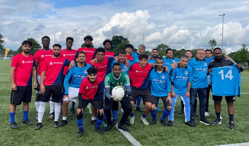 Zwei Fußballmannschaften posieren für ein Foto auf dem Sportplatz: Die Johanniter und das Team Sport