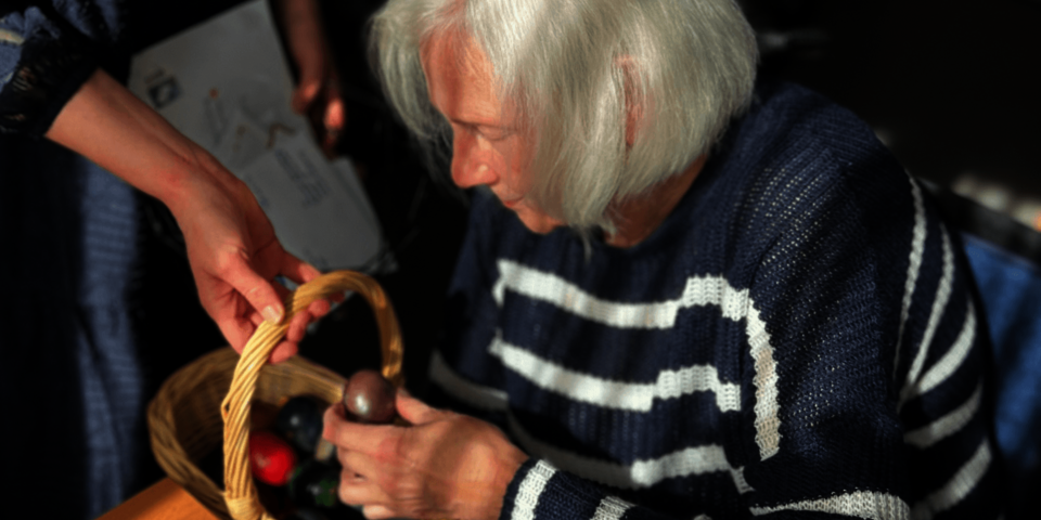 Eine Frau nimmt ein buntes Ei aus einem Körbchen