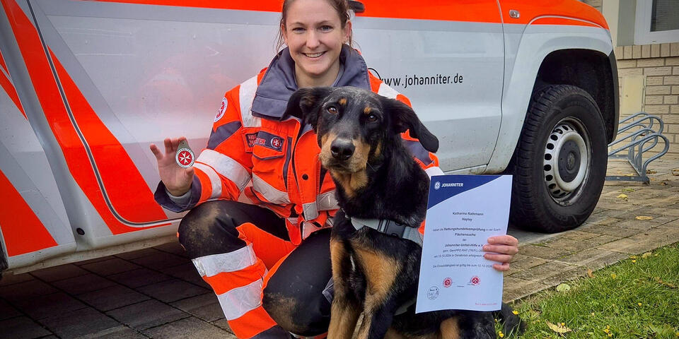 Eine Johanniterin mit Hund hält eine Urkunde hoch