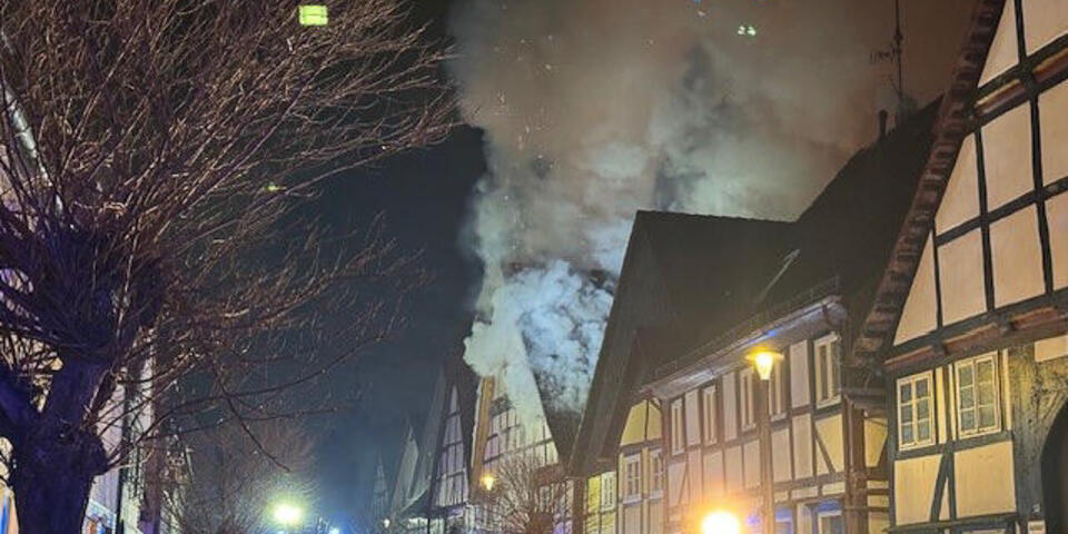 Einsatzkräfte vor einem brennendem Haus