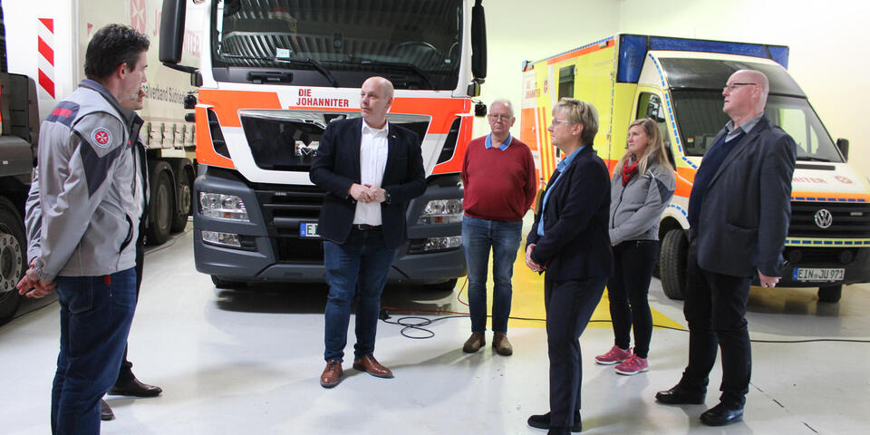 Eine Gruppe von Menschen vor Einsatzfahrzeugen in einer Halle