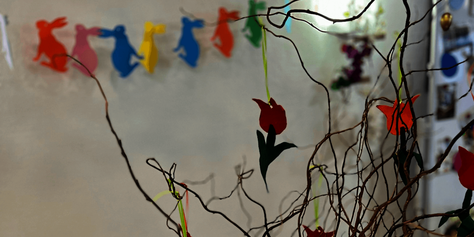 Ein Strauß aus dünnen Zweigen, an denen gebastelte Tulpen hängen