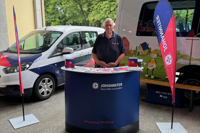 Ein Johanniter steht am Stand der Ausbildung wird Werbematerial für die Johanniter