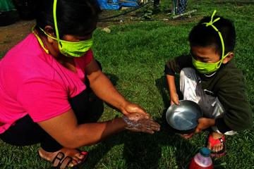 Eine Frau und ein Kind waschen sich die Hände. Beide tragen eine Maske