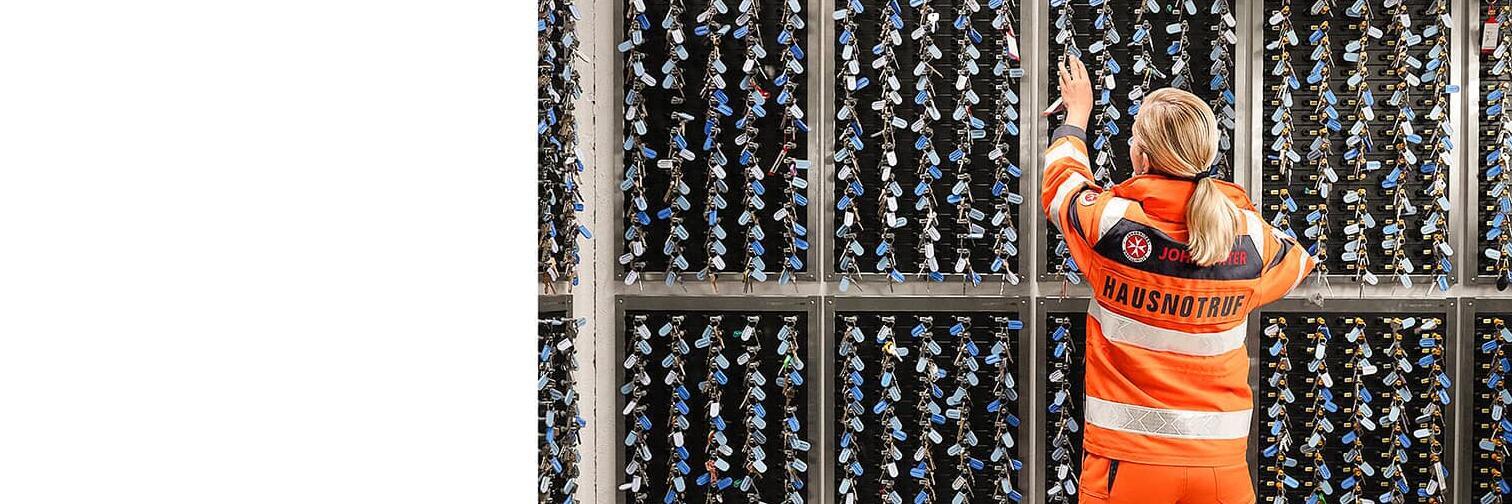 Johanniterin steht vor dem wandhohen Aufbewahrungsregal für die Hausschlüssel.