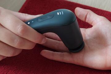 Ein Massagegerät wird auf einer Hand-Innenfläche angewendet.