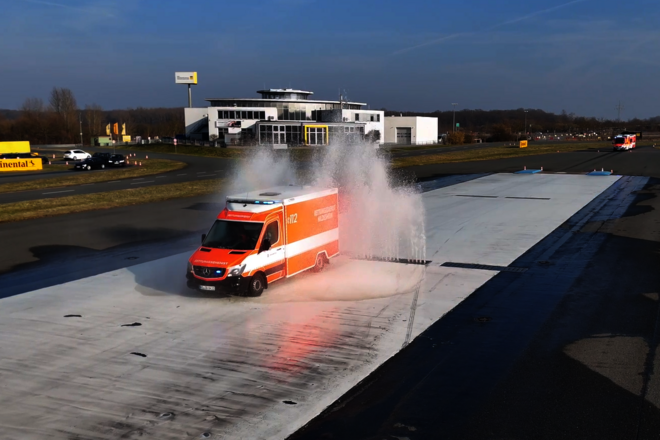 Ein Rettungswagen fährt durch Wasserfontänen