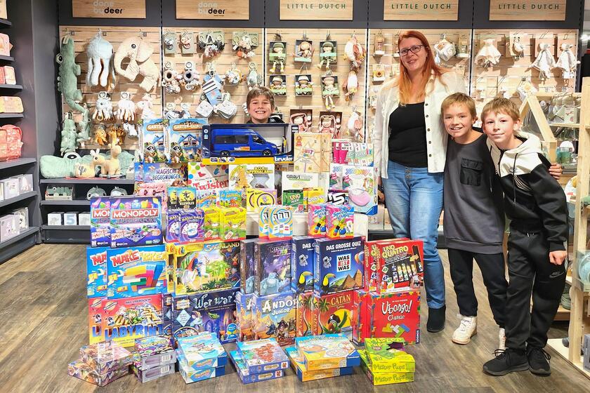 Einrichtungsleitung Susanne Gehrmann mit drei Hortkindern bei der Übergabe des Spielwarenpakets