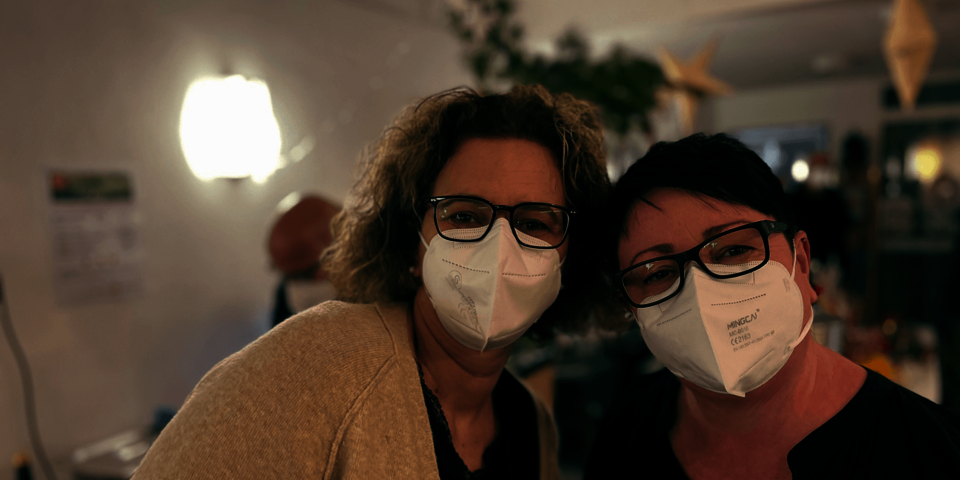 Zwei Frauen, beide tragen Masken und eine Brille