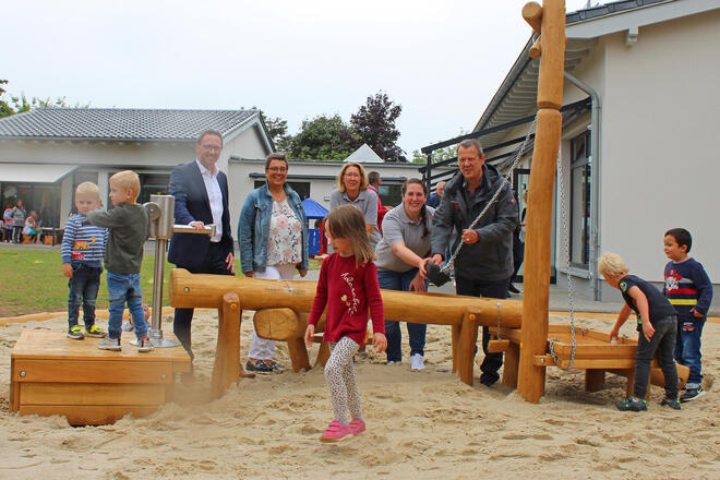 Erwachsene und Kinder an einem Außenspielgerät