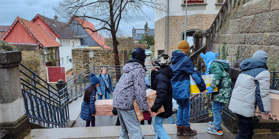 Kinder tragen Pakete eine Treppe hinab.
