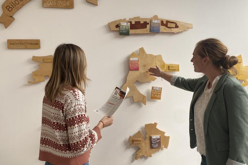 Zwei Frauen betrachten eine Wand auf der die Bildungsschwerpunkte der Kinderkrippe visualisiert wurden