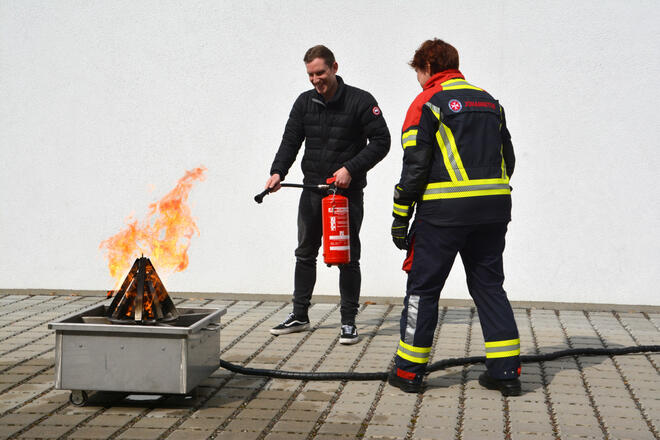Praktisches Feuerlöschtraining mit Unterstützung durch Fachpersonal.