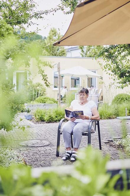 Eine Bewohnerin liest im Garten ein Buch