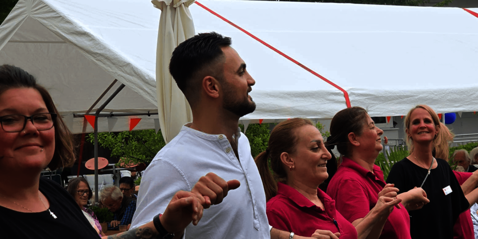 Eine Reihe Menschen hält sich tanzend an den Händen.