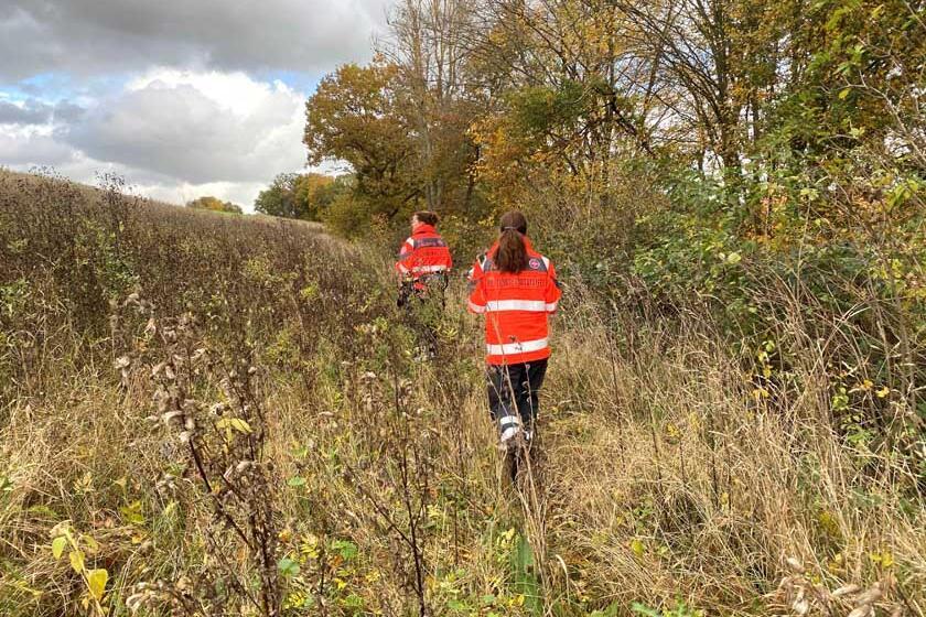 Mitgliederinnen der Rettungshundestaffel Südniedersachsen suchen in einem Feld am Waldrand nach der Vermissten.