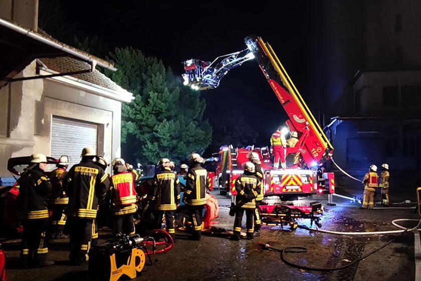 Feuerwehr- und Rettungsdiensteinsatzkräfte bei der gemeinsamen Übung. Zu sehen ist auch ein Einsatzfahrzeug der Feuerwehr.