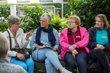 Personen im gespräch auf der Plauderbank im Freien